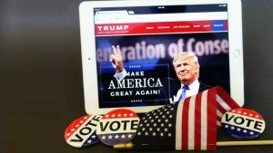 Donald Trump's image on an iPad, next to VOTE buttons and a flag