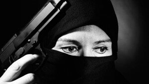 Woman wearing a headscarf and niqab holding a pistol