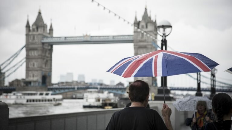 Man with a British flag umbrella walking along the Thames in London