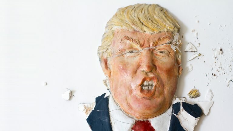 A cracked, crumbling ceramic mask of Donald Trump